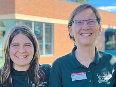 two new staff members wearing green polos and smiling