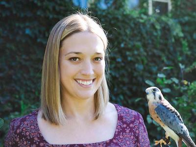 Dr. Victoria Hall poses with a bird perched in hand