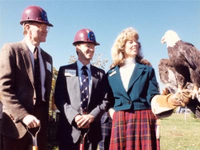 Raptor Center cofounders Dr. Gary Duke, Dr. Pat Redig, and Daisy Ritter pose outside with a bald eagle