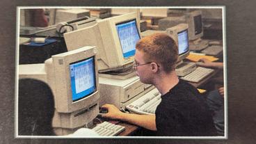 A man sits at a old school computer in a lab