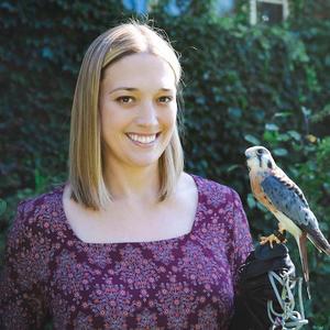 Dr. Victoria Hall poses with a bird perched in hand