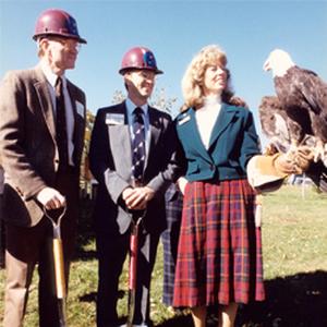 Raptor Center cofounders Dr. Gary Duke, Dr. Pat Redig, and Daisy Ritter pose outside with a bald eagle